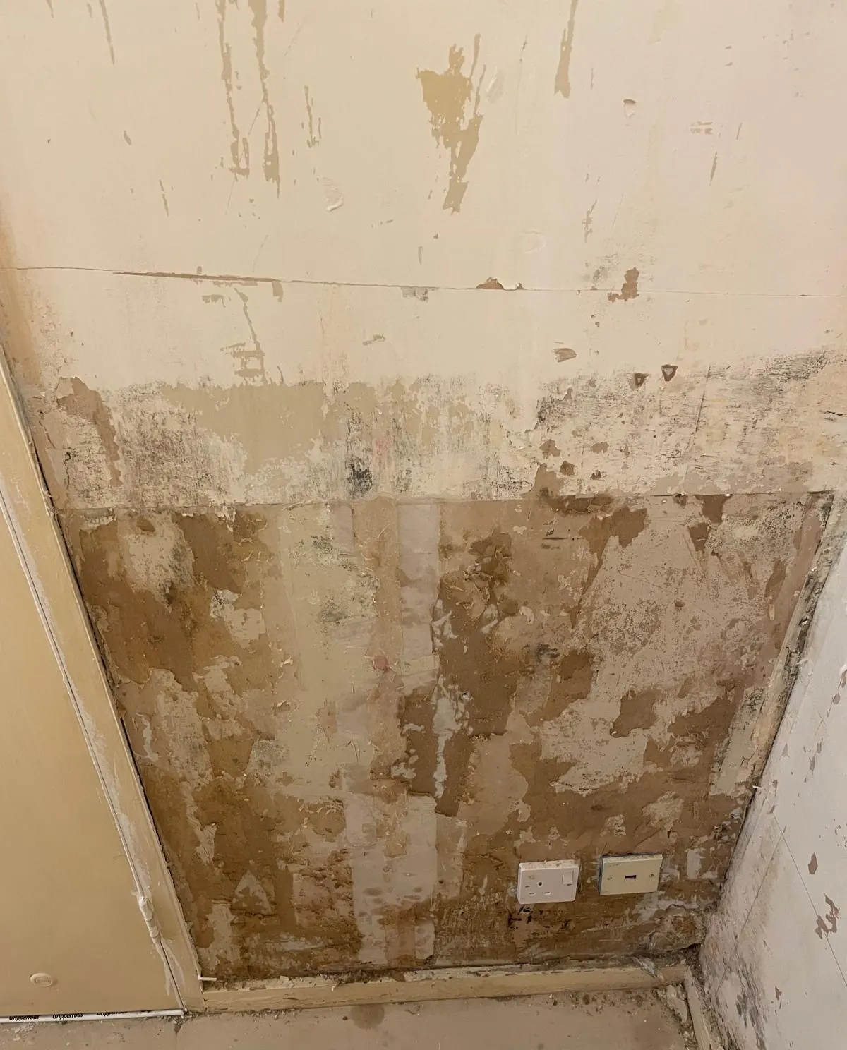 Living-room wall with damaged and patched plaster before the work